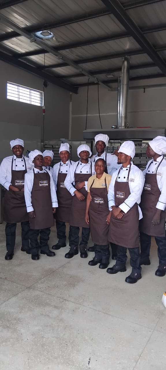 The full Tastebell bakery team in front of the ovens